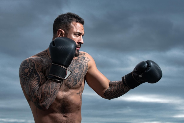 Deporte boxeo deportista boxeador peleando en el cielo de fondo fuerte atlético hombre con guantes de boxeo...