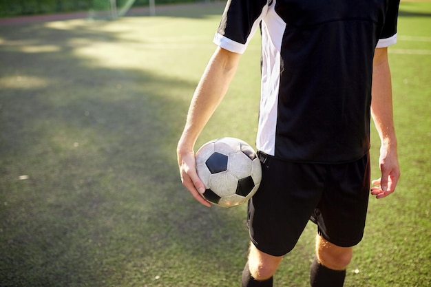 deporte, entrenamiento de fútbol y concepto de personas: primer plano del jugador de fútbol con pelota en el campo