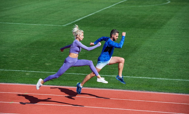 El deporte es nuestra vida. corredores en pista de atletismo. desafío y competencia. aguante. resistencia energética. encajar deportistas saltando. Entrenador deportivo de hombre y mujer corriendo. entrenamiento de pareja de fitness al aire libre.