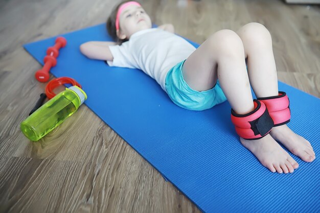 Deporte y estilo de vida saludable Niño haciendo deporte en casa. Colchoneta de yoga con mancuernas y cuerda para saltar. Fondo deportivo con concepto de ejercicios en casa.