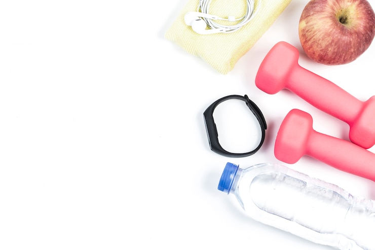 Deporte, estilo de vida saludable y objetos concepto - close up de pesas, fitness tracker, auriculares y botella de agua sobre fondo blanco