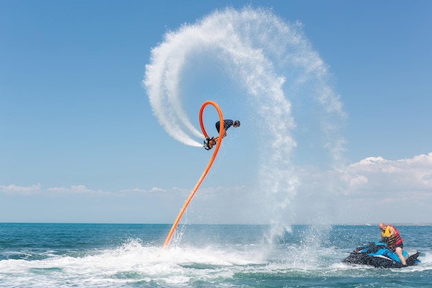 Deporte extremo acuático Un hombre vuela en un flyboard de agua