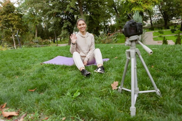 Deporte de fitness y concepto de blogs de video La mujer en forma graba vlogs deportivos usando una cámara en un trípode al aire libre