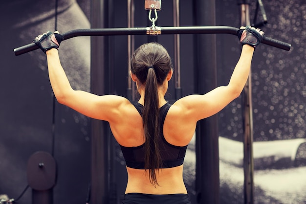 deporte, fitness, culturismo, estilo de vida y concepto de personas - mujer flexionando los músculos en la máquina de cable en el gimnasio