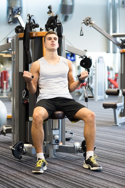 deporte, fitness, equipo, estilo de vida y concepto de personas - hombre haciendo ejercicio en una máquina de gimnasio