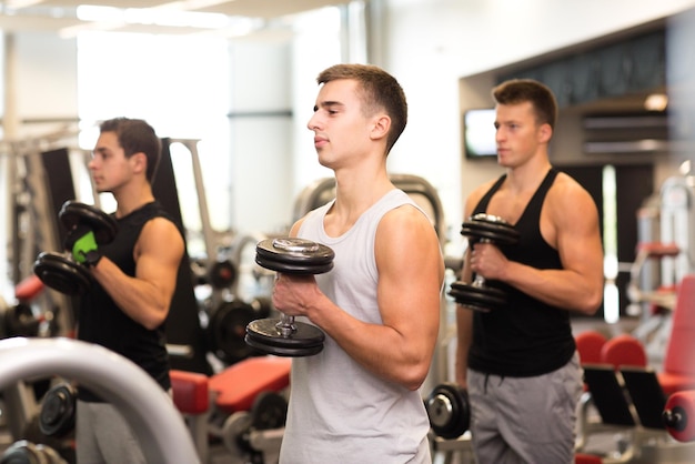 deporte, fitness, estilo de vida y concepto de personas - grupo de hombres con pesas en el gimnasio