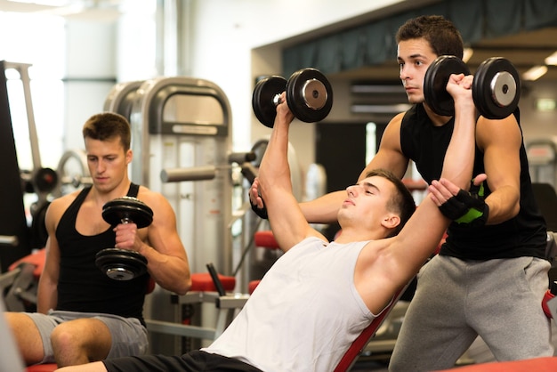 deporte, fitness, estilo de vida y concepto de personas - grupo de hombres con pesas en el gimnasio