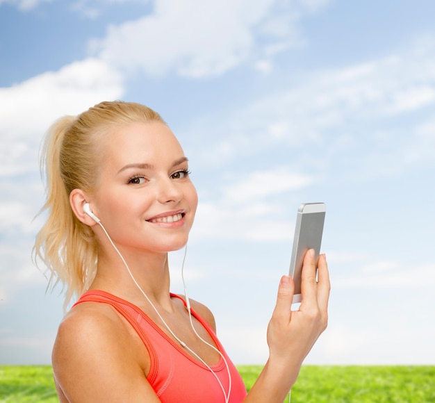 deporte, fitness, tecnología, internet y atención médica - mujer deportiva sonriente con teléfono inteligente y auriculares