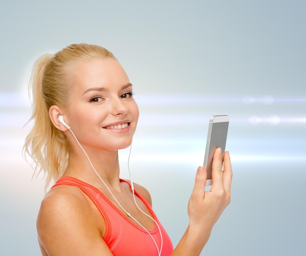 deporte, fitness, tecnología, internet y atención médica - mujer deportiva sonriente con teléfono inteligente y auriculares