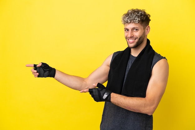 Deporte hombre caucásico aislado sobre fondo amarillo apuntando con el dedo hacia un lado y presentando un producto