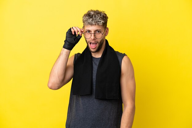 Deporte hombre caucásico aislado sobre fondo amarillo con gafas y sorprendido