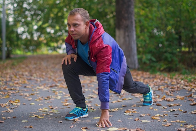 Deporte hombre estirando en el parque otoño haciendo ejercicios Conceptos de fitness