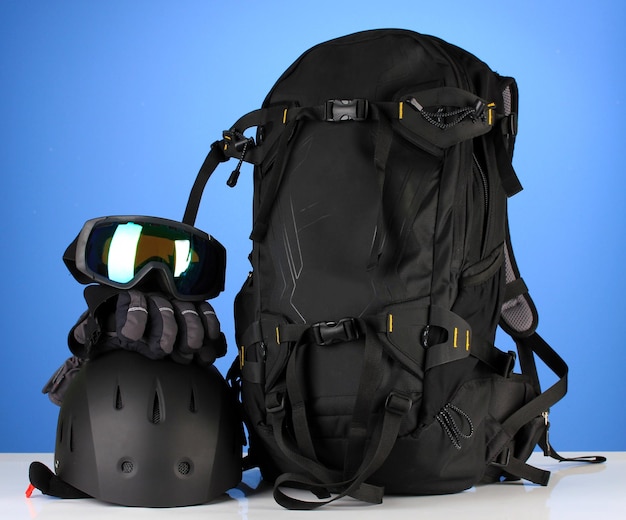 Deporte de invierno gafas casco y guantes mochila sobre fondo azul.