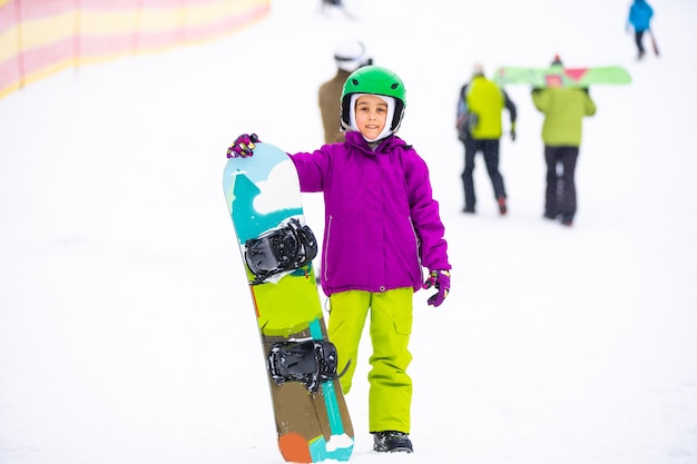 Deporte de invierno de snowboard. niña aprendiendo a hacer snowboard, vistiendo ropa abrigada de invierno. Fondo de invierno.