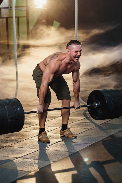 Deporte joven haciendo cuclillas con barra en el gimnasio.