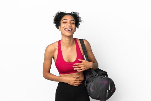 Deporte joven mujer afroamericana con bolsa de deporte aislado sobre fondo azul sonriendo mucho