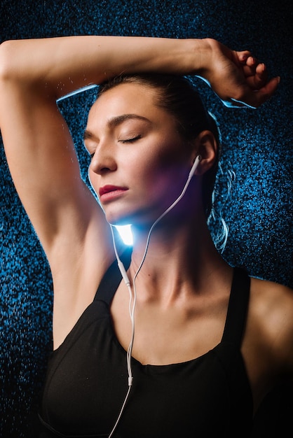 Deporte joven mujer con auriculares sobre fondo negro