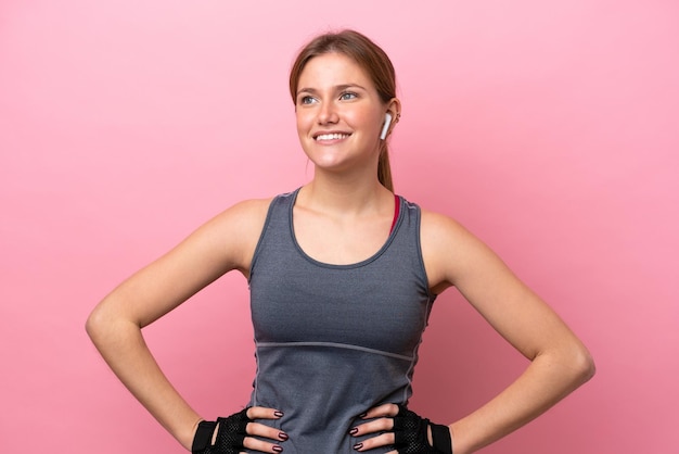 Foto deporte joven mujer caucásica aislada sobre fondo rosa posando con los brazos en la cadera y sonriendo