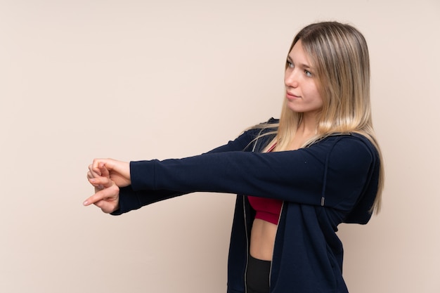 Foto deporte joven mujer rubia sobre estiramiento de pared aislada