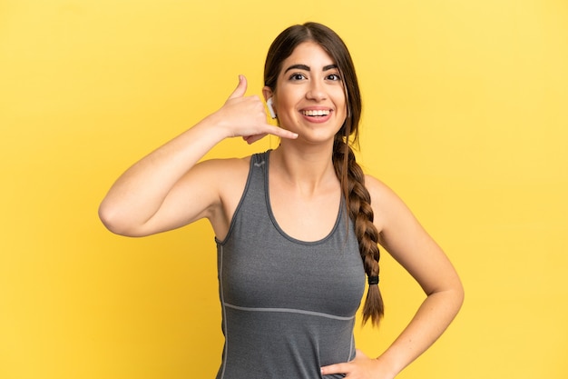 Deporte mujer caucásica aislada sobre fondo amarillo haciendo gesto de teléfono. Llámame señal