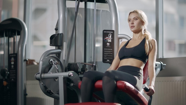 Deporte mujer haciendo ejercicio de pierna en máquina de fitness en gimnasio