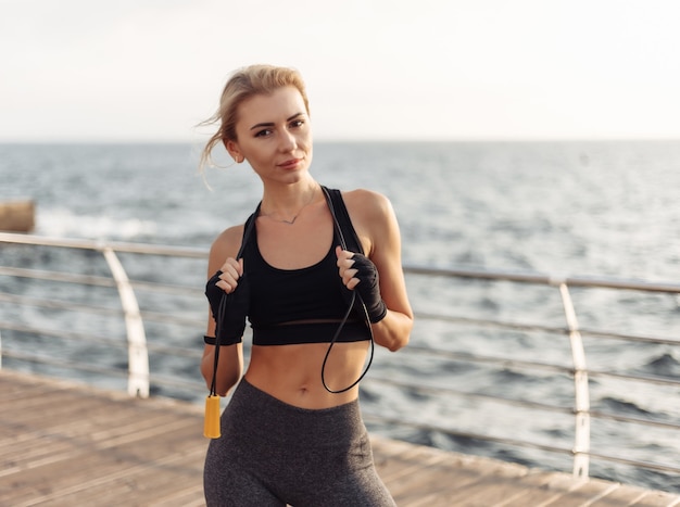 Deporte mujer kickboxer con las manos vendadas en vendajes y saltar la cuerda posando