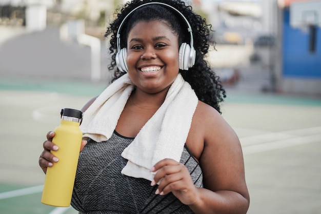 Deporte mujer negra con curvas escuchando música con auriculares - Centrarse en la cara