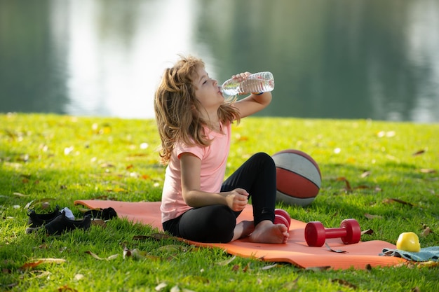 Deporte niño niño niño comiendo alimentos saludables bebiendo agua después del ejercicio