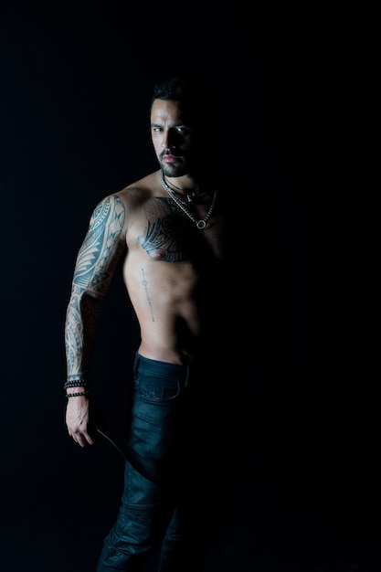 Deporte o fitness y cuidado corporal. Hombre barbudo con cuerpo tatuado. Macho con sexy torso desnudo en jeans. Modelo de tatuaje con six pack y ab. Atleta o deportista con pecho y barriga musculosos.