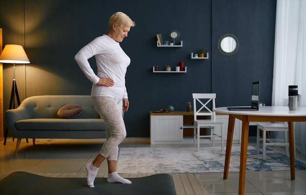 Foto deporte sonriente mujer madura haciendo ejercicios en casa. estilo de vida senior activo