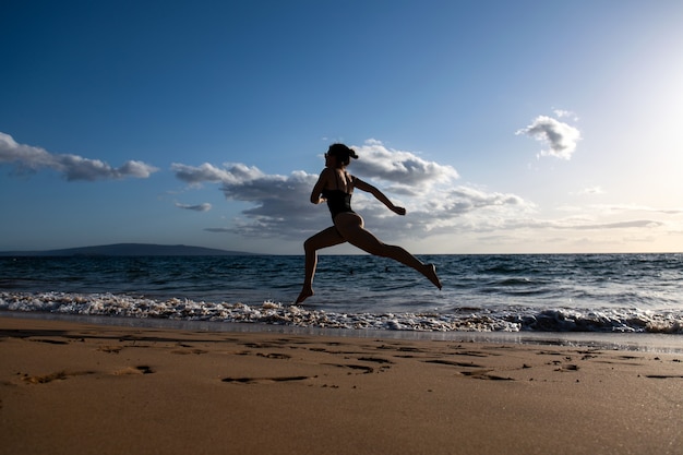 Deportes al aire libre. Mujer que corre a lo largo de la orilla del mar en la mañana. Mujer fitness haciendo ejercicio en la playa.