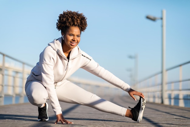 Deportes al aire libre sonriente joven mujer negra en Activewear entrenamiento fuera