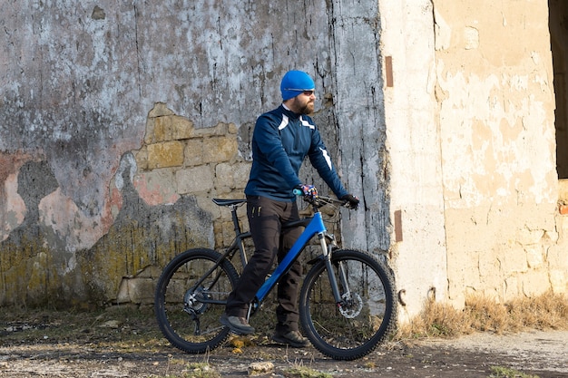 Deportes barbudo brutal en una bicicleta de montaña moderna. Un ciclista en un lugar desierto de sal junto al lago.