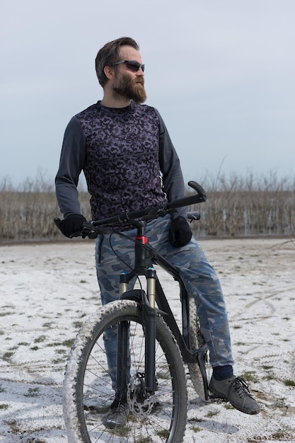 Deportes brutal chico barbudo en una bicicleta de montaña moderna Un ciclista en un lugar desierto de sal junto al lago