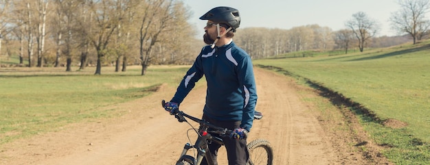 Deportes brutal chico barbudo en una bicicleta de montaña moderna Ciclista en las verdes colinas en la primavera