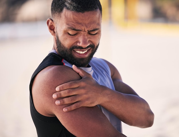 Deportes con dolor de brazo y hombre en una playa para entrenamiento de fitness y rendimiento de voleibol con problema Lesión en el hombro y jugador masculino con artritis fibromialgia o crisis de osteoporosis durante el entrenamiento