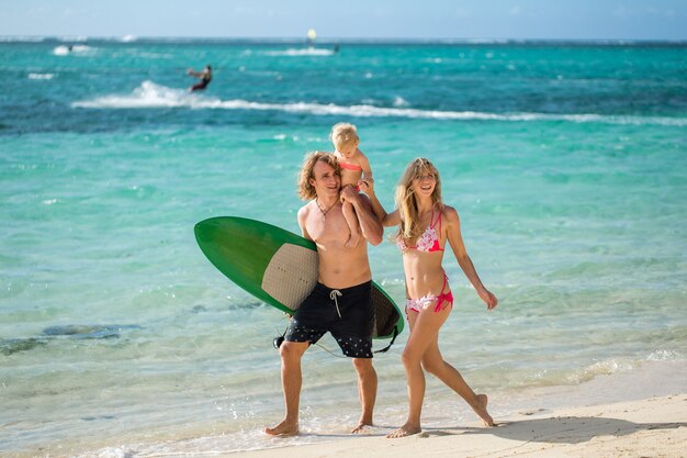 Deportes familia papá, mamá e hija caminando por la playa