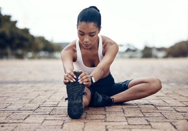 Foto deportes de fitness y mujer estirando las piernas en calentamiento para comenzar a entrenar ejercicio y entrenamiento cardiovascular en lisboa runner atleta y chica flexible sosteniendo zapatos para correr para un estiramiento saludable de los isquiotibiales