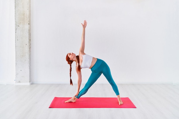 Foto deportes flexibles joven practica ejercicios de yoga en la clase de estudio