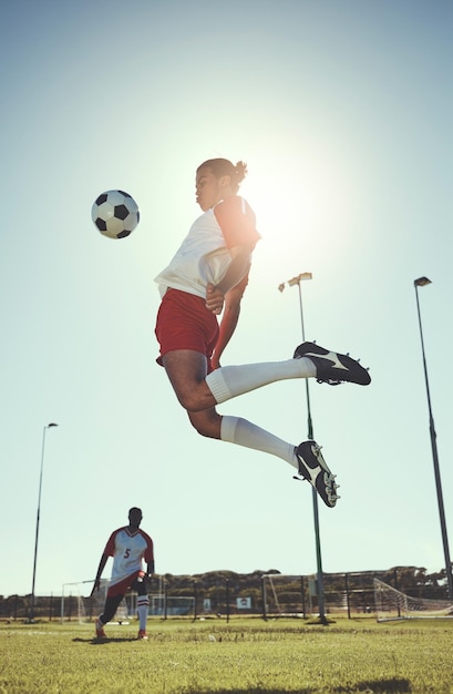 Deportes de fútbol y entrenamiento con un atleta que juega con una pelota en un campo o campo de hierba para hacer ejercicio y estar en forma Salto de fútbol y entrenamiento con un hombre en un juego o partido deportivo