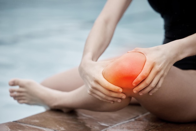 Deportes con lesiones de rodilla y mujer en la piscina con dolor médico tensión corporal y emergencia muscular Piernas herida roja y accidente de agua por entrenamiento de artritis y anatomía del atleta para ayuda de primeros auxilios