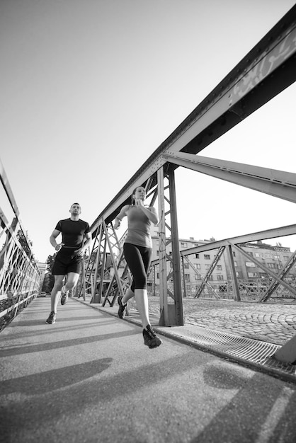 deportes urbanos, pareja joven sana corriendo por el puente en la ciudad en la mañana soleada