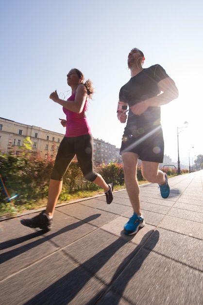 deportes urbanos, pareja joven sana trotando en la ciudad en la mañana soleada