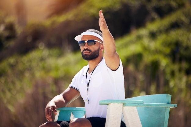 Deportes de verano y un árbitro de voleibol en la playa en una silla para reglas o regulaciones de autoridad durante un juego Profesional de la salud o competencia con un hombre arbitrando un partido al aire libre durante el día