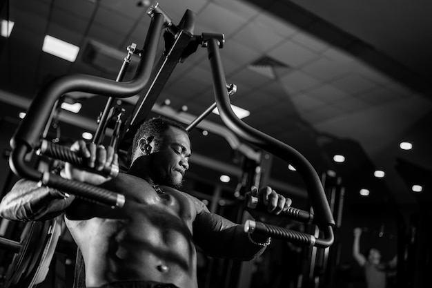 Foto deportista africano con cuerpo perfecto entrena en equipo deportivo fondo claro oscuro fotografía en blanco y negro