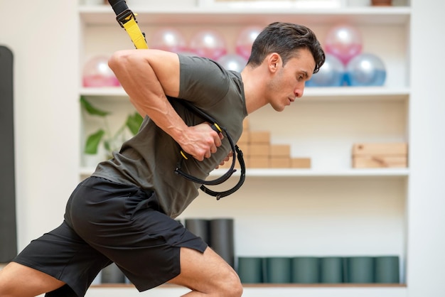 Deportista atlético haciendo ejercicio en cuerdas TRX en el gimnasio