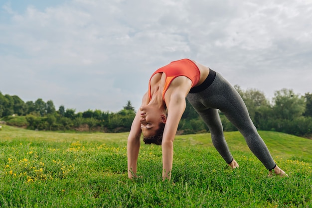 Deportista atractiva delgada estirando su cuerpo disfrutando de un ambiente de naturaleza pacífica