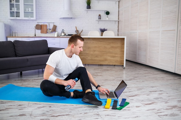 Un deportista con camiseta practica deporte en casa en su espacioso y luminoso apartamento con un interior minimalista. Deportes por internet