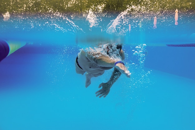 Deportista caucásico nadando con omóplatos bajo el agua