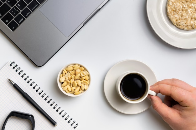 Deportista comiendo rondas de arroz crujientes con cacahuetes, taza de café cerca de la computadora portátil